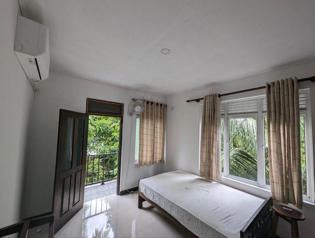 um quarto com uma cama e uma grande janela em awana em Ambalangoda