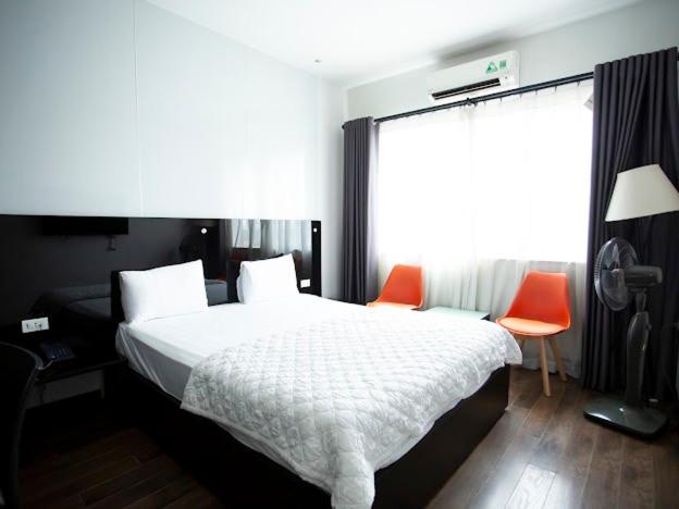 a bedroom with a bed and two orange chairs at Ánh Hồng Hottel in Hanoi