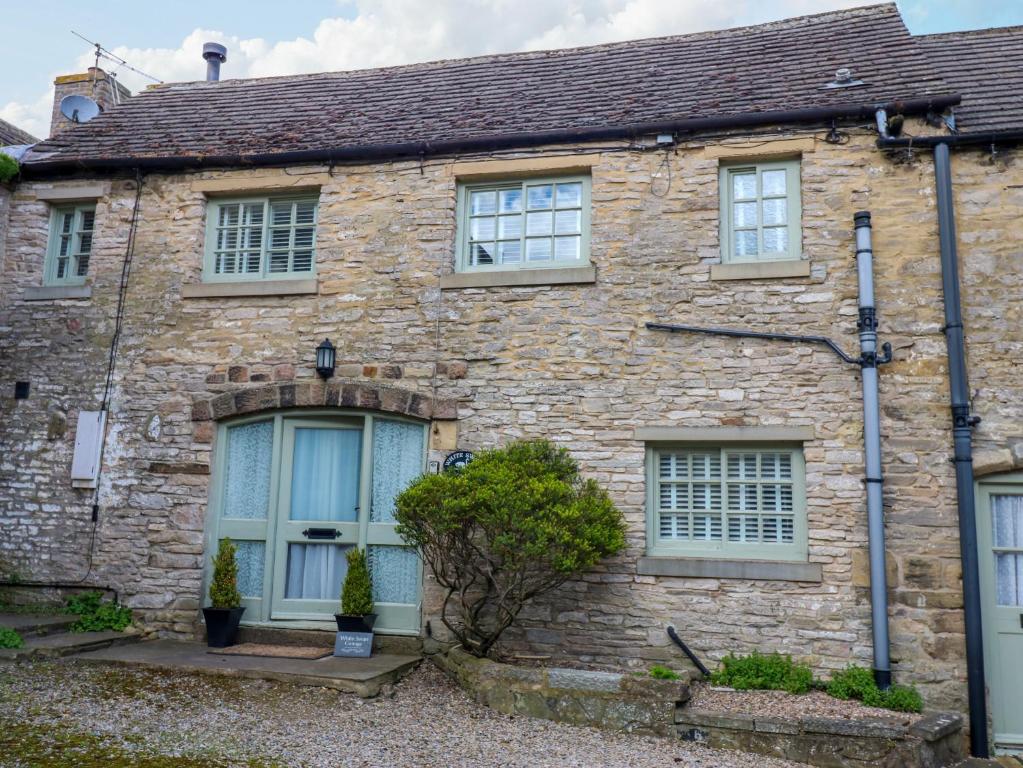 an old stone house with blue doors and windows at White Swan Cottage in Leyburn
