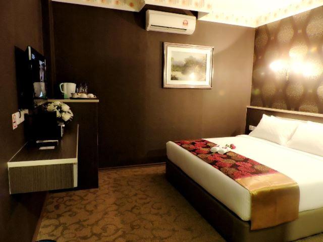 a hotel room with a bed and a night stand at The Ardens Hotel - Nong Chik, Kolam Air, Johor Bahru in Johor Bahru