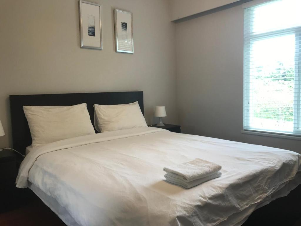 um quarto com uma cama branca com duas toalhas em Edmonds Home em Burnaby