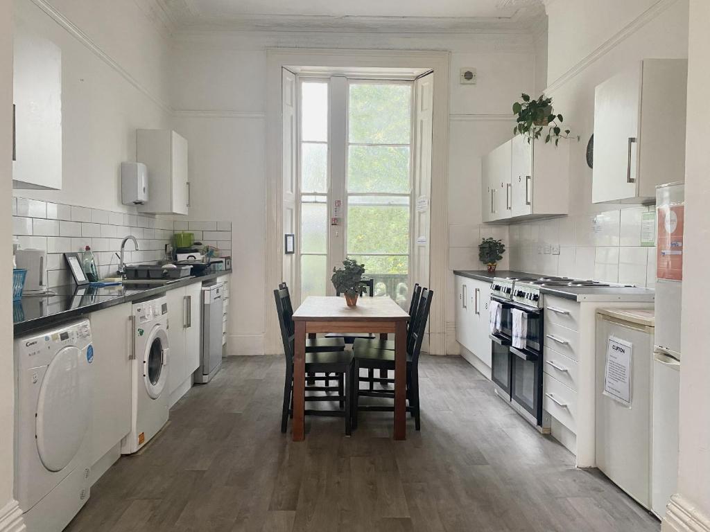 a kitchen with a table with chairs and a sink at St Paul's Road Townhouse by Clifton Short Lets in Bristol