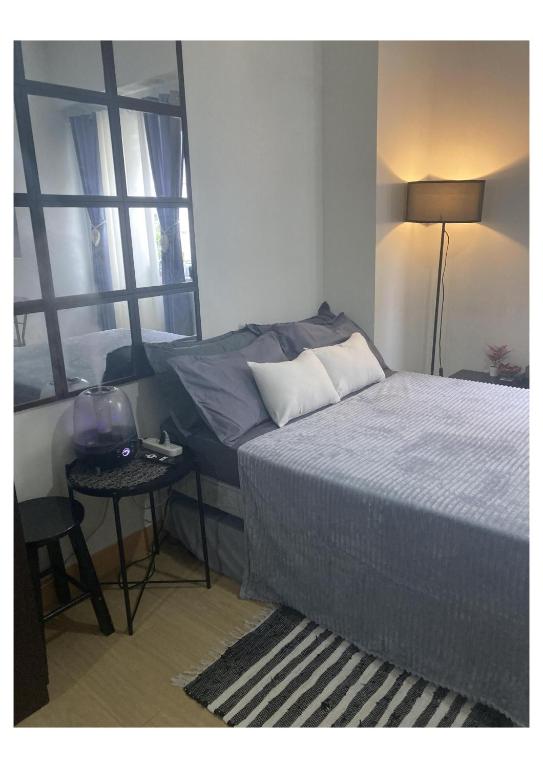 een slaapkamer met een bed, een tafel en een raam bij Boheme Condotel at Trees Residences Studio2 in Manilla