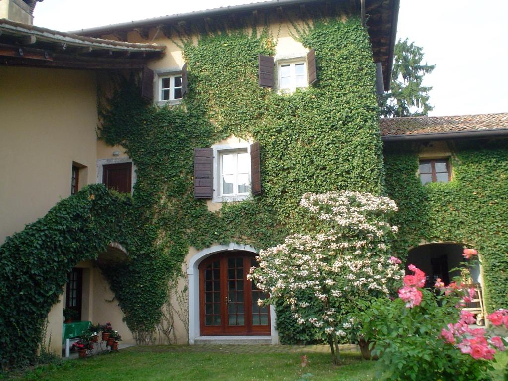 una casa ricoperta di edera con fiori nel cortile di Casa Antica Mosaici a Trivignano Udinese