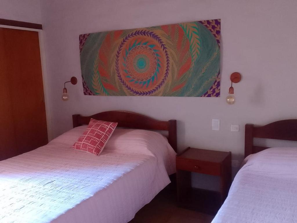 a bedroom with two beds and a painting on the wall at Hotel Hualum in Villa Dolores