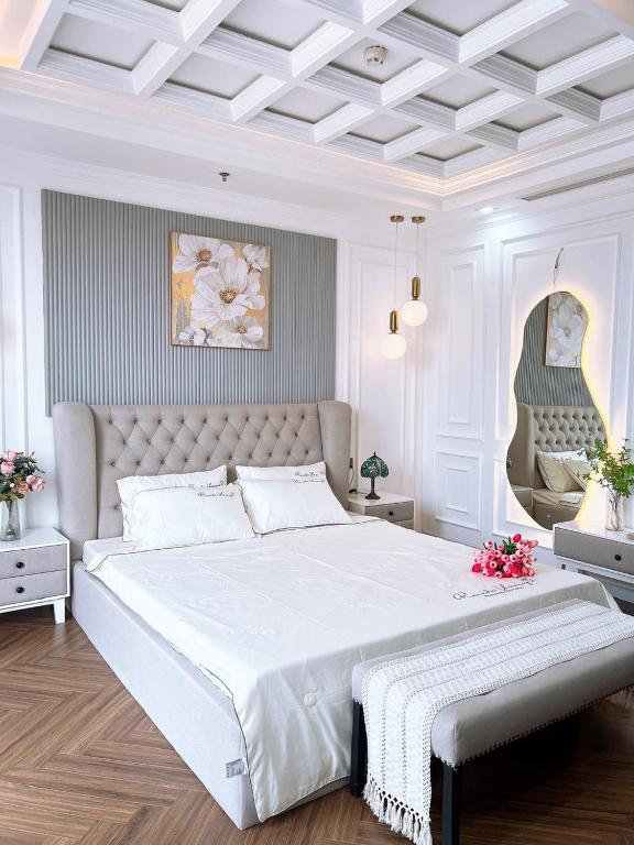 a white bedroom with a large white bed with a bench at LaLa Penthouse in Hue
