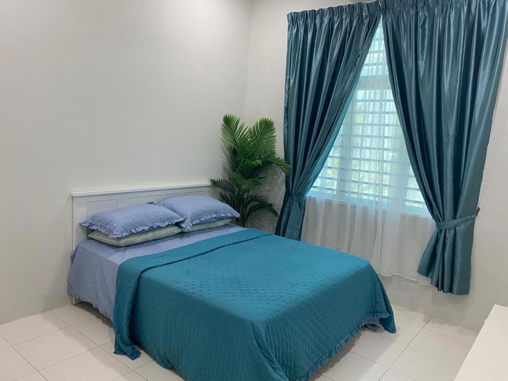 um quarto com uma cama com lençóis azuis e uma janela em Qaisara Homestay em Kampong Alor Gajah