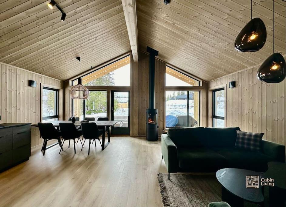 a living room with a couch and a table and chairs at Brand new cabin in the center of Skeikampen in Svingvoll