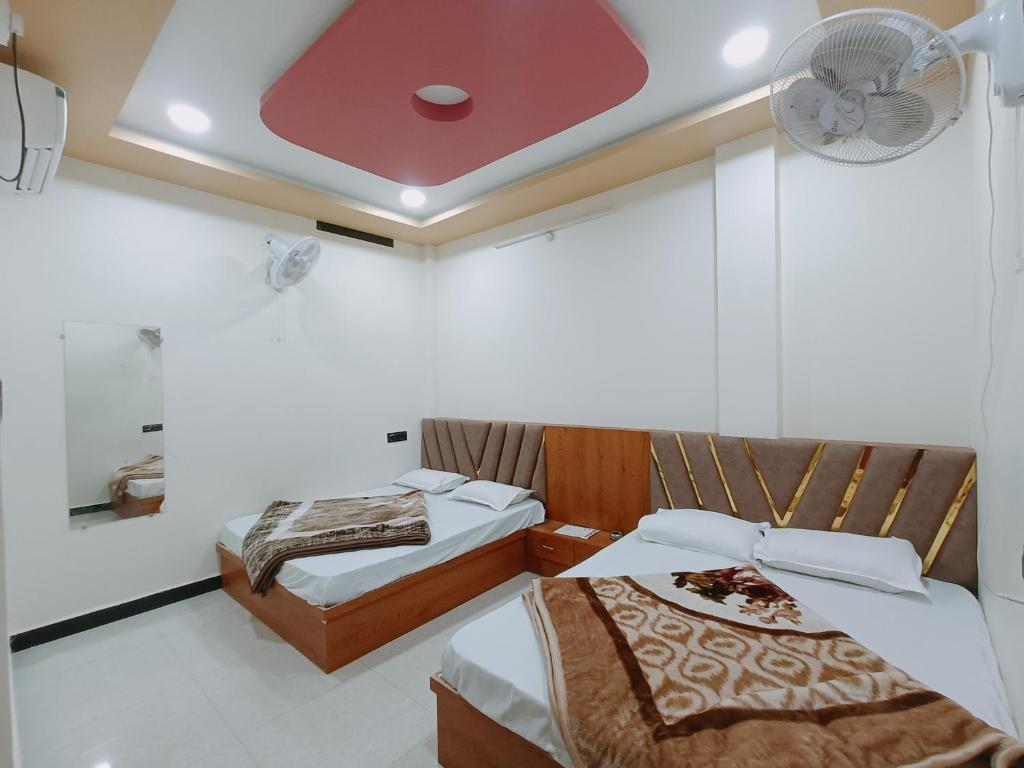 een kamer met 2 bedden en een plafondventilator bij Hotel Shreem in Ujjain