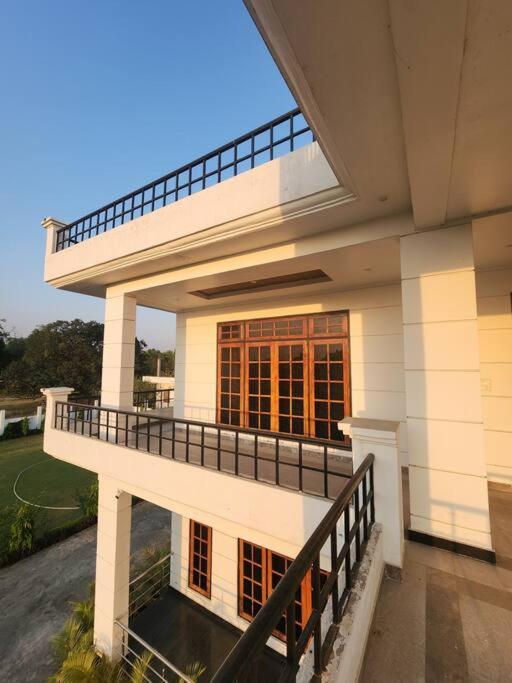 Cette grande maison blanche dispose d'un balcon et d'un escalier. dans l'établissement Shanti Niwas, à Varanasi