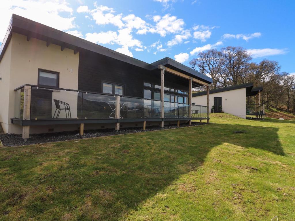 a black and white house with a large yard at 2 Strathtay Lodges in Aberfeldy