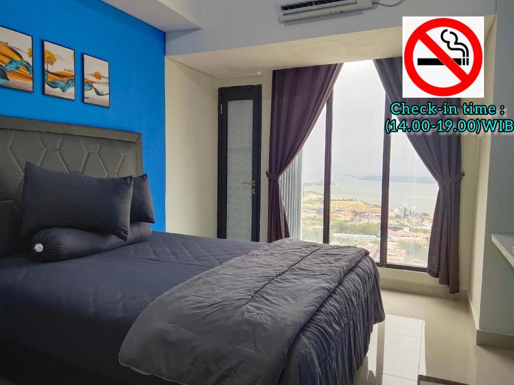 a bedroom with a bed with a no smoking sign at Comodo Apartemen Pollux Habibie Rooftop-SeaView in Batam Center