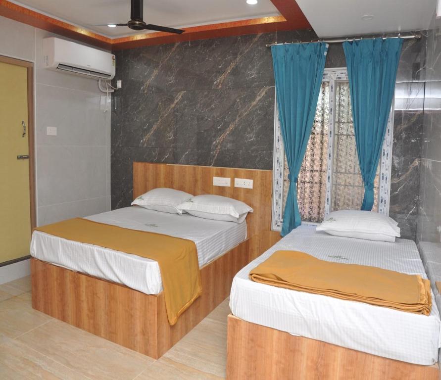 two beds in a room with blue curtains at SDD Grand in Tiruvannāmalai
