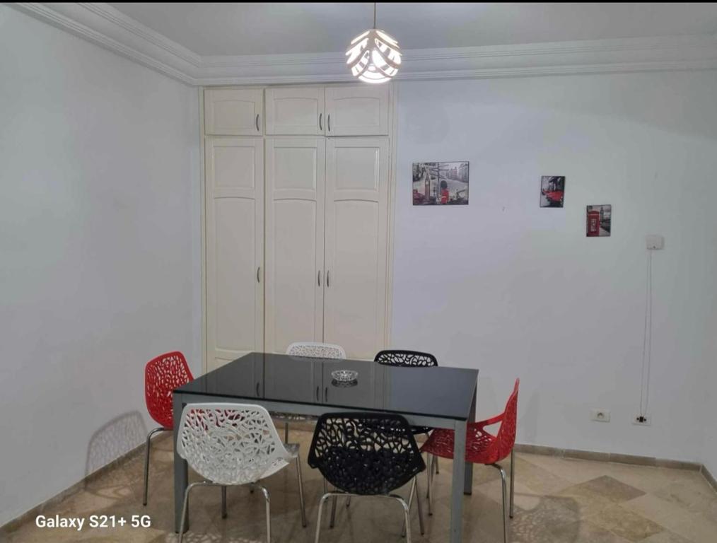 uma sala de jantar com uma mesa preta e cadeiras vermelhas em Superbe logement Majida boulila em Sfax
