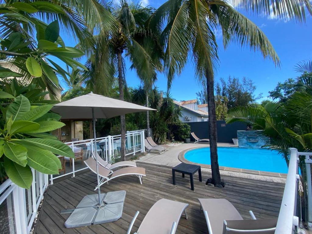 una terraza con sillas, una piscina y palmeras en Le Vacoa, en La Saline-Les-Bains