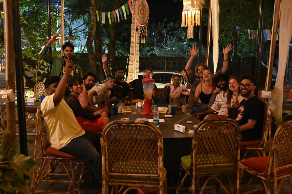 a group of people sitting around a table with their hands in the air at BunkNBrew in Palolem