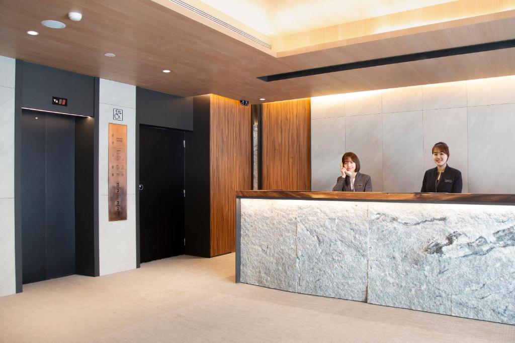 two people sitting at a counter in a lobby at Dandy Hotel-Daan Park Branch in Taipei