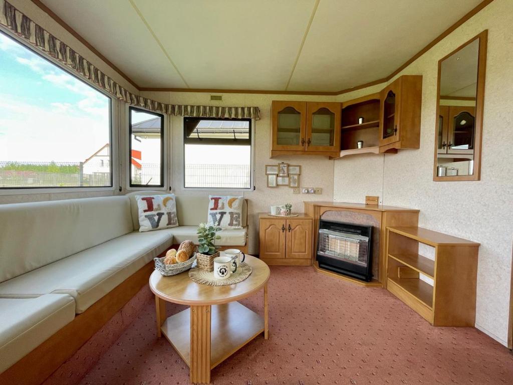 ein Wohnzimmer mit einem Sofa und einem Tisch in der Unterkunft Domek holenderski in Rydzewo