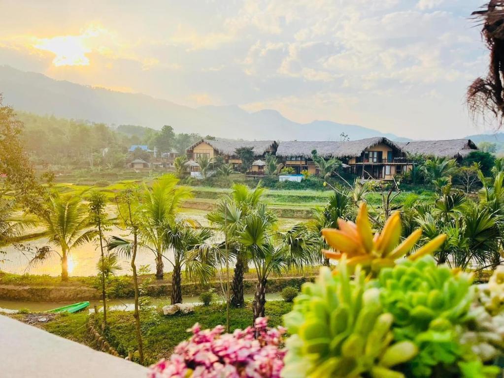 widok na ośrodek z palmami i domami w obiekcie Mai Chau Onsen Retreat w mieście Mai Châu