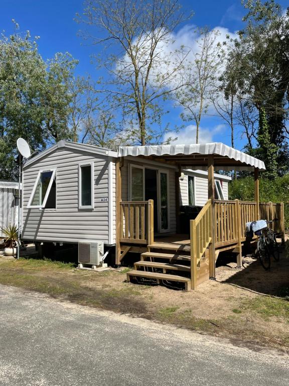 a tiny house with a porch and a deck at Mobil home Le Bois Masson A34 in Saint-Jean-de-Monts