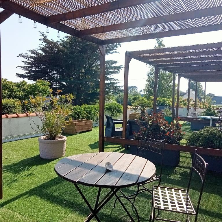 a picnic table and chairs under a wooden pergola at Les Chambres de Kerzerho in Erdeven