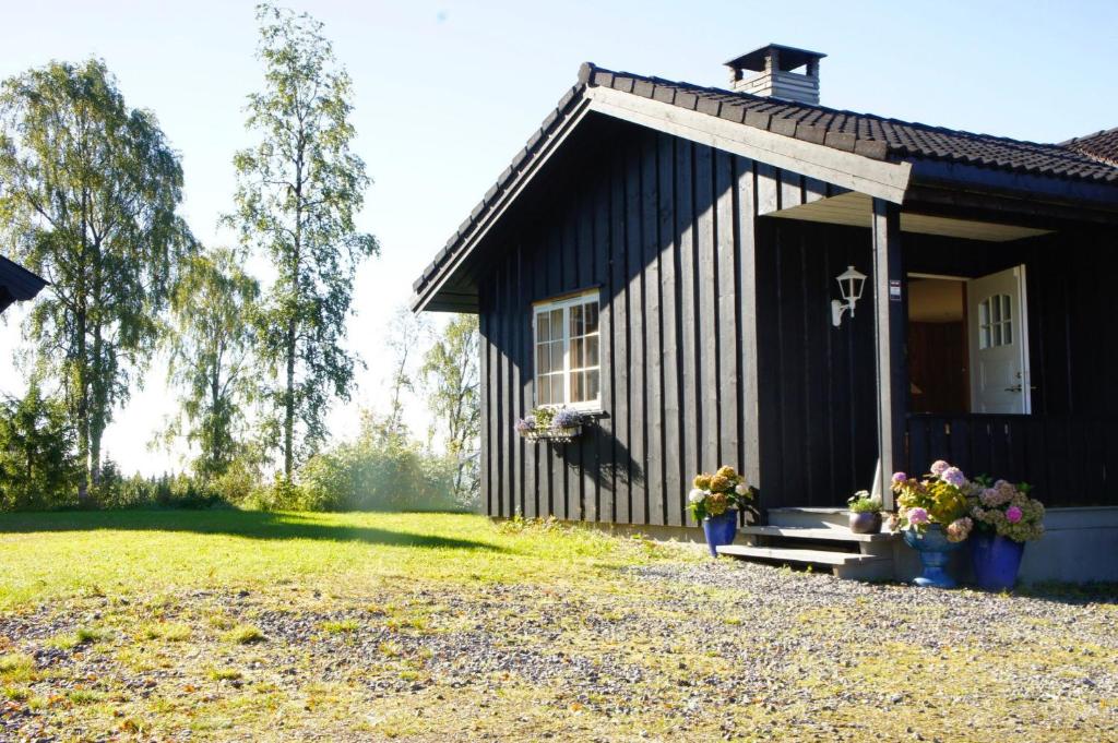 un pequeño edificio negro con flores delante en Nordgards Hagen, en Lillehammer