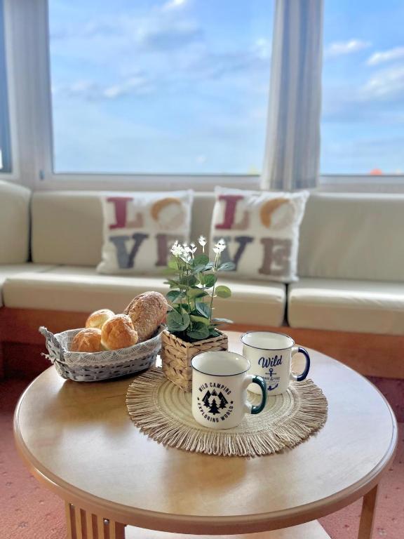 a coffee table with two cups and bread on it at Domek holenderski in Rydzewo