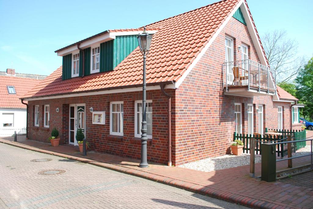 a brick building with a green roof on a street at Hotel und Ferienwohnung Rodenbäck in Neuharlingersiel