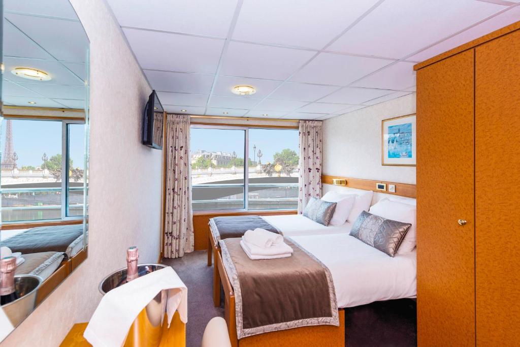 a room with a bed and a balcony on a boat at Bateau Botticelli by CroisiEurope in Paris