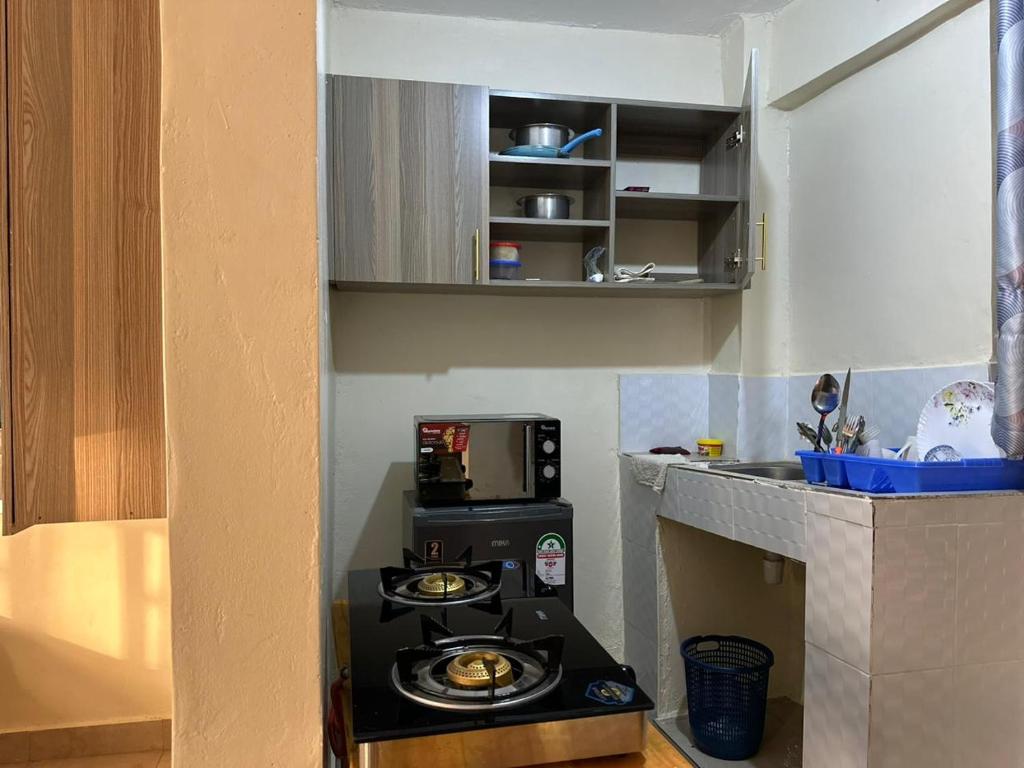 a small kitchen with a stove and a microwave at Amani stays Embu-white in Embu