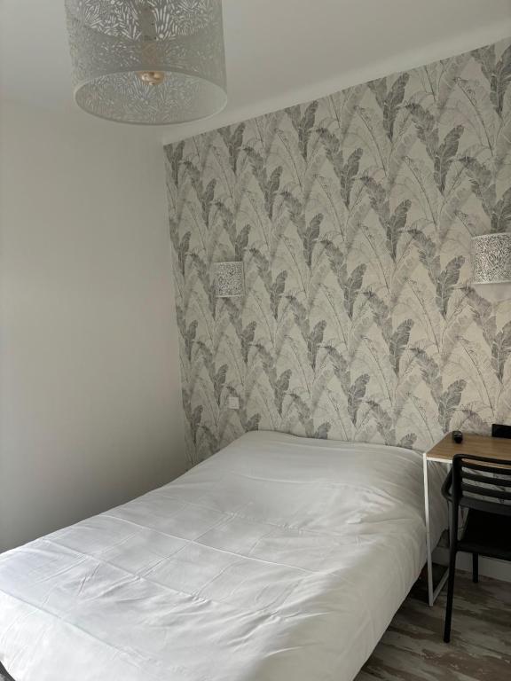 a bedroom with a white bed and a wall at Hôtel de La gare-Les Floralies in Poitiers