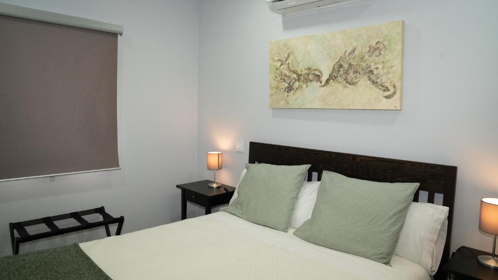 Pelayos de la PresaにあるAPARTAMENTOS PRADERAS PANTANO SAN JUANのベッドルーム1室(白いシーツと緑の枕が備わるベッド1台付)