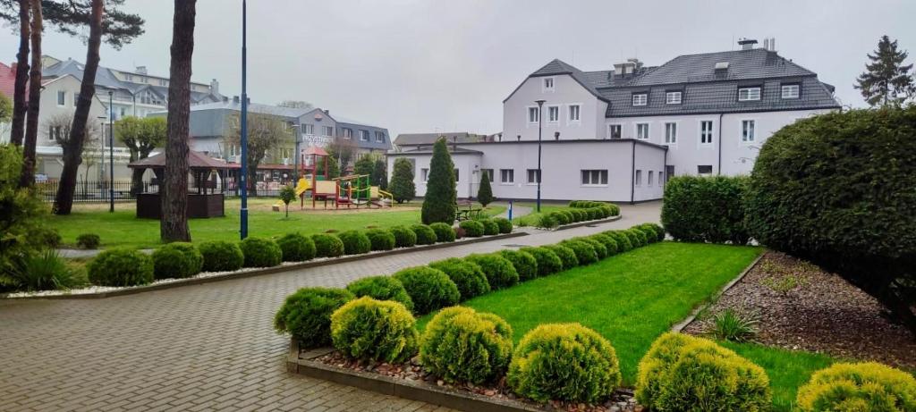 a row of hedges in a park with houses at Złota Rybka Natura Tour in Dziwnówek