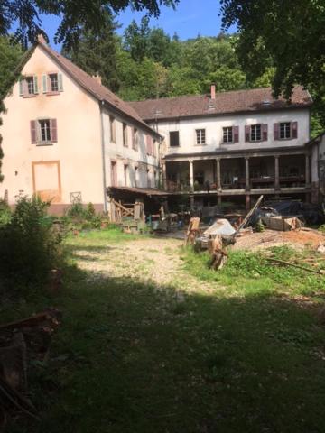 una grande casa bianca seduta in mezzo a un cortile di Les anciens thermes a Soultzbach-les-Bains