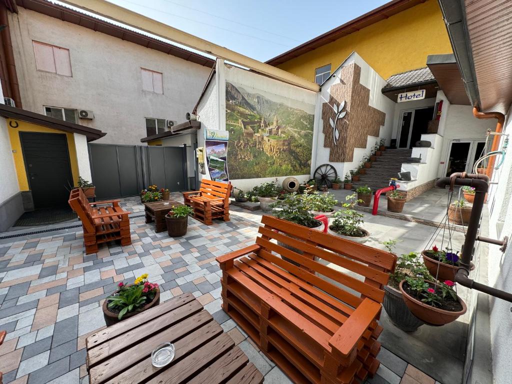 un patio con un banco de madera y algunas plantas en NO PROBLEM en Ereván