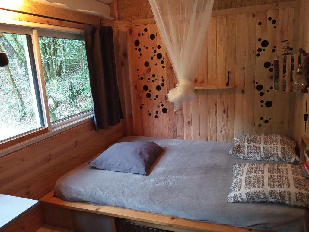 a bed in the corner of a room with a window at Echappée sauvage in Masquières