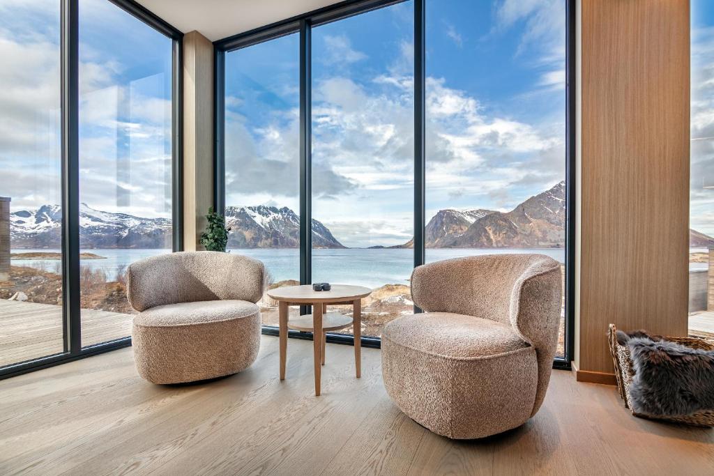 two chairs and a table in a room with large windows at Northern Cabin Retreat in Lyngværet