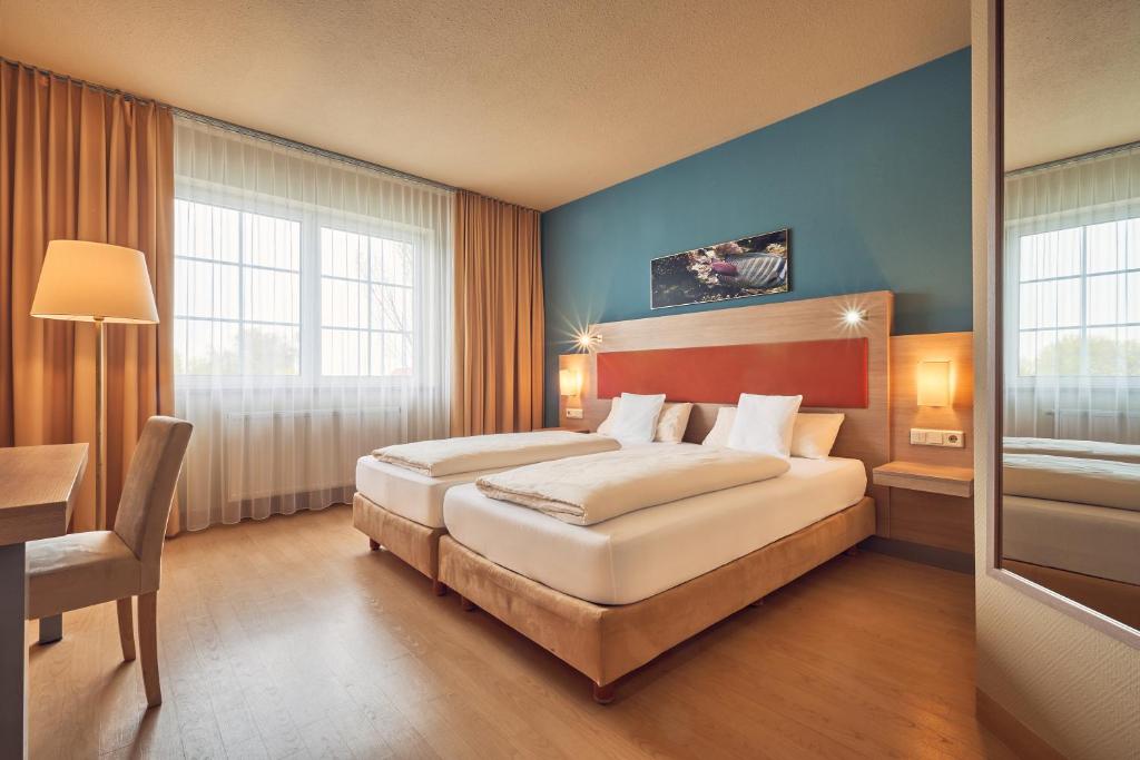 a hotel room with two beds and a desk at AKZENT Hotel Aufkirchen in Aufkirchen