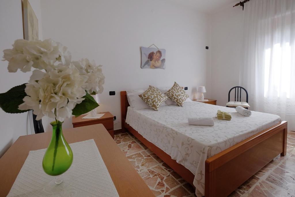 una camera da letto con un letto e un vaso di fiori su un tavolo di Casa Lucia a Teulada