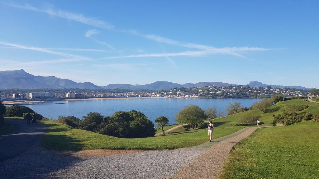 une femme debout sur un chemin à côté d'un lac dans l'établissement Meublé 4 pers saint Jean de luz, à Saint-Jean-de-Luz
