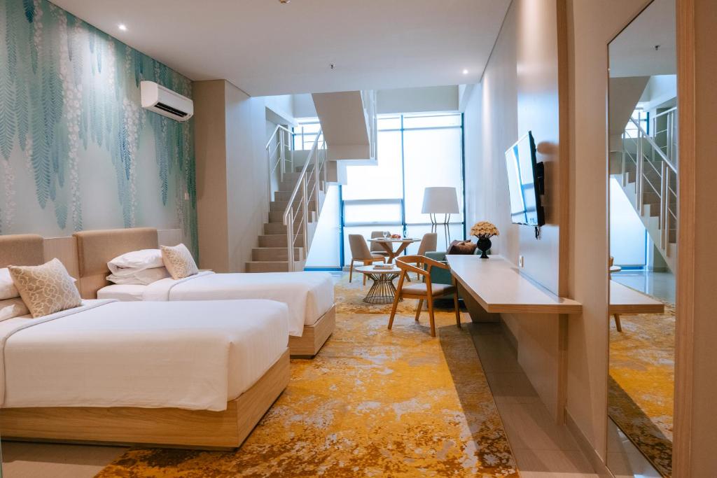 a hotel room with two beds and a desk at Skysuites Residence in Kedungbaruk