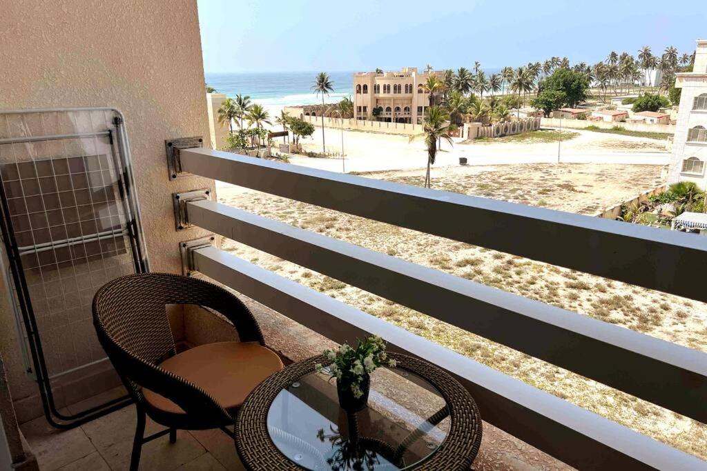 uma varanda com mesa e cadeiras e vista para a praia em Beautfiul Salalah Beach Apartment - Flat 404 em Salalah