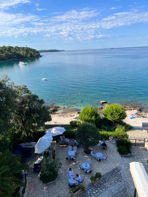 a group of people sitting under umbrellas on a beach at Rooms Figarola in Rovinj