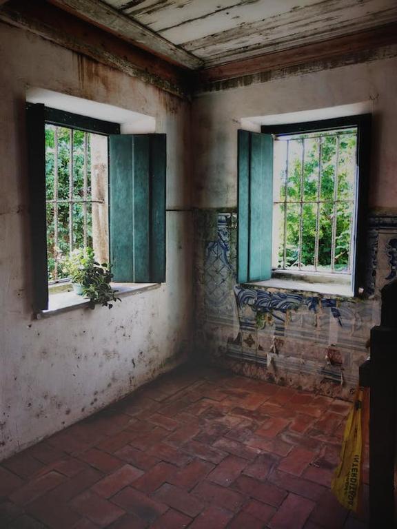 Hotel JAFFNAs في Kilinochchi: غرفة فارغة مع نافذتين في مبنى قديم