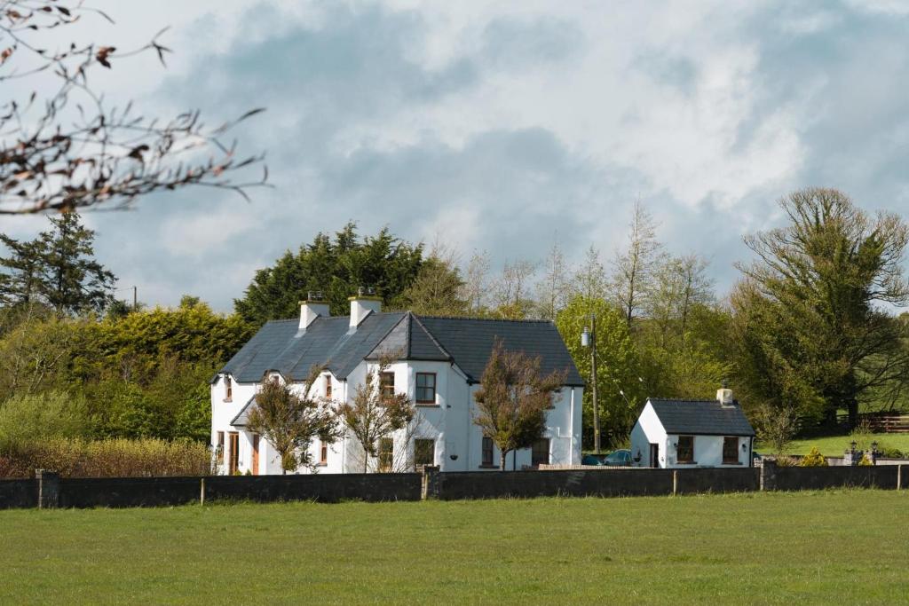 una casa blanca con un techo negro en un campo en Glenvela guest house, en Castlerea