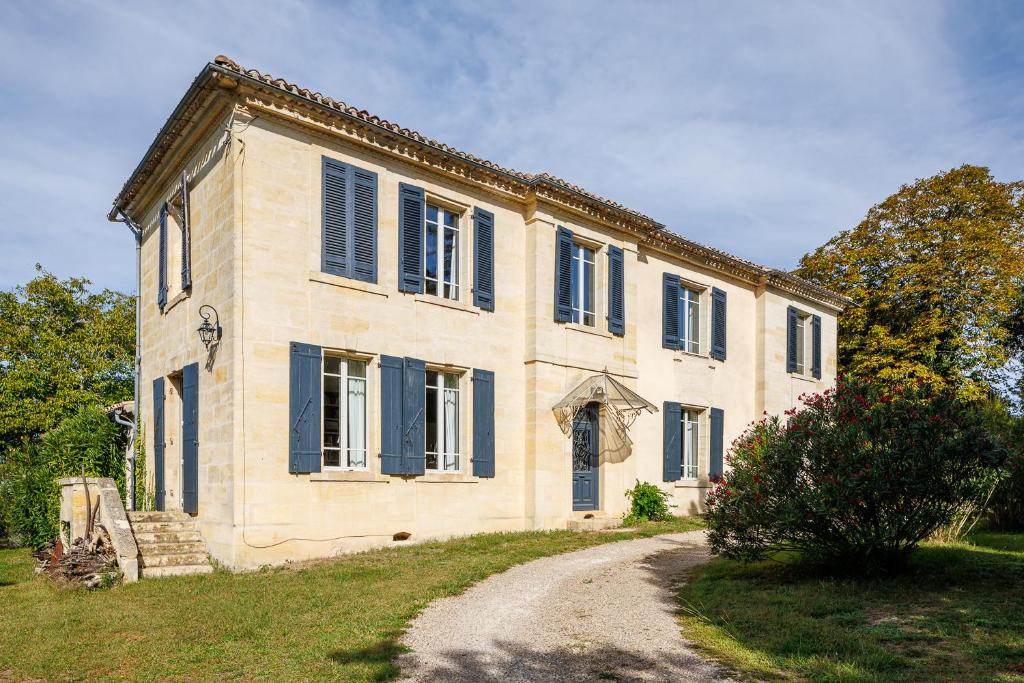une ancienne maison en pierre avec des volets bleus et un chemin de terre dans l'établissement Maison de maître proche Bordeaux, à Carignan