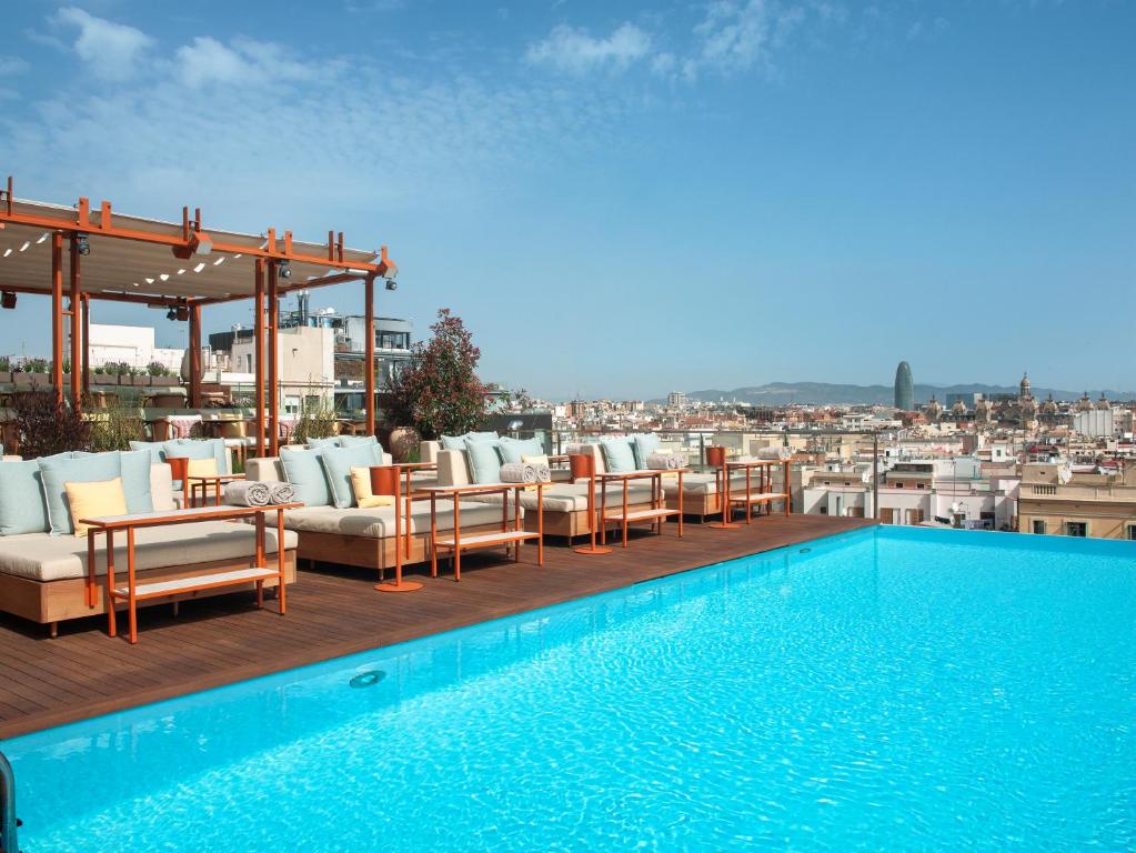 uma piscina com cadeiras e mesas num edifício em Grand Hotel Central, Small Luxury Hotels em Barcelona