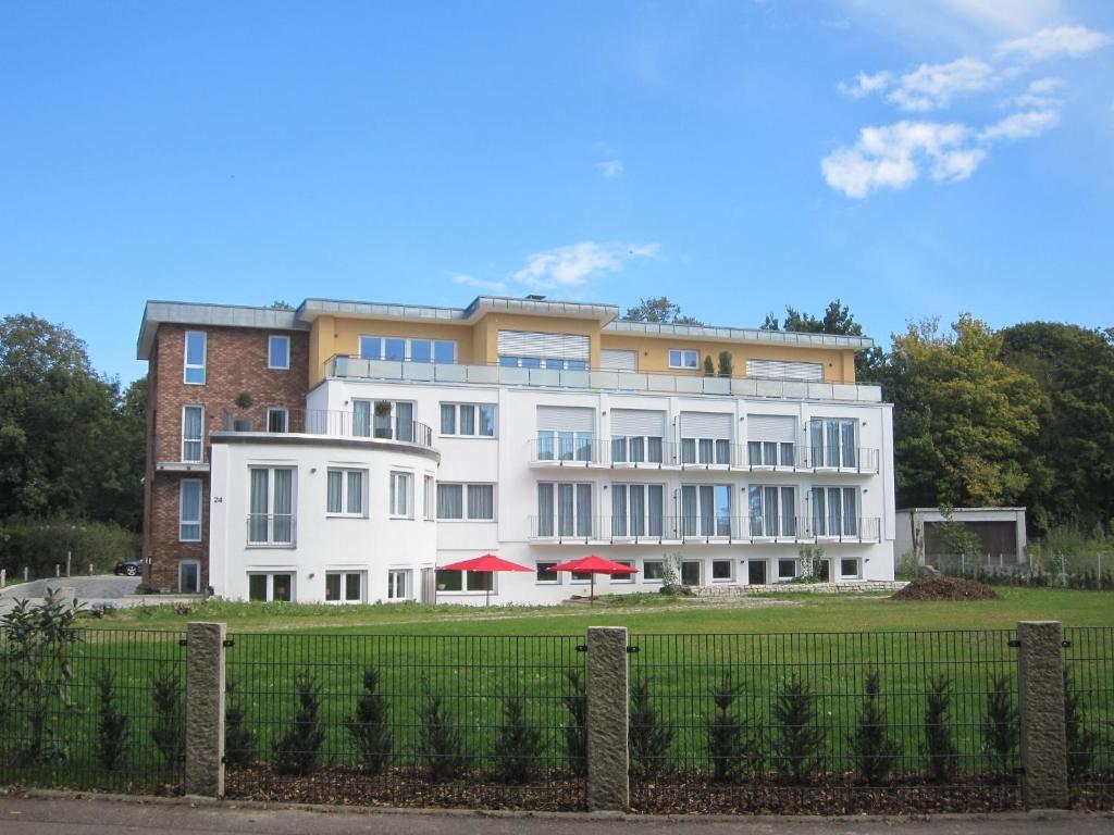 un grand bâtiment blanc avec une clôture devant lui dans l'établissement Hotel Vier Jahreszeiten an den Thermen, à Bad Krozingen