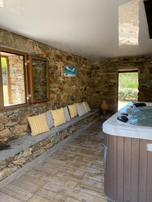 Cette chambre est dotée d'un mur en pierre et d'une baignoire. dans l'établissement Villa Pleine campagne Jacuzzi 15 mn Saint Florent, à Santo-Pietro-di-Tenda