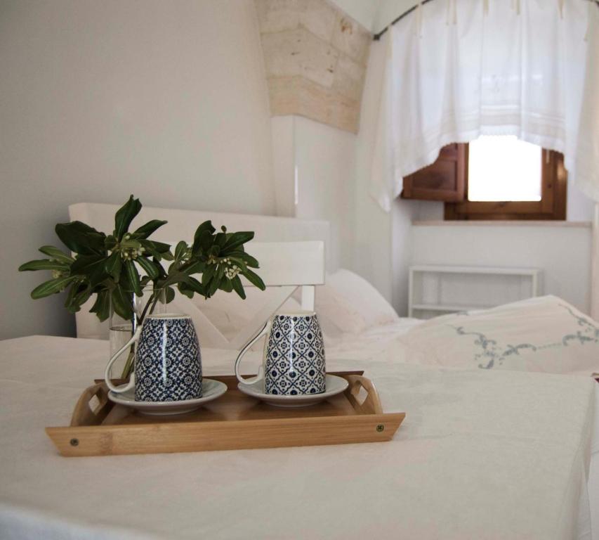 una bandeja con dos jarrones y una planta en una cama en Casa Nonna Renzina, en Locorotondo